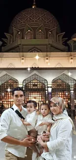 Family in front of illuminated mosque at night.