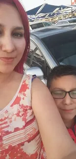 Family posing in front of car outdoors.