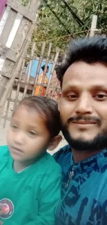 A father and child enjoying a moment outdoors with greenery in the background.