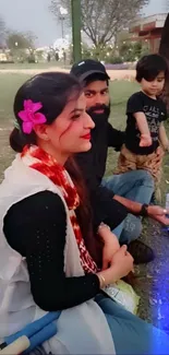 Family relaxing in park with child, flower in hair.