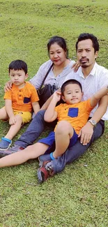 Family enjoying a picnic on green grass, kids in orange shirts.