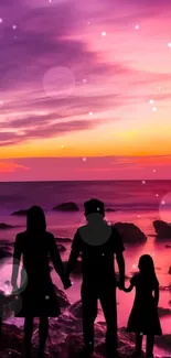 Silhouette of a family by the beach at sunset with pink and purple sky.