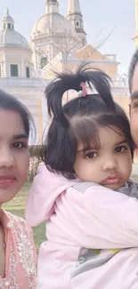 Family smiling in front of a temple during the day.