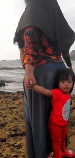 Mother and child walking on rocky beach.