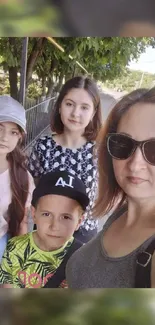 Family photo under green trees on a sunny day.