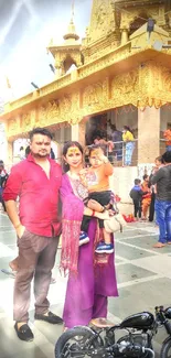 Family posing at a golden temple with vibrant cultural attire.