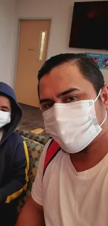 Father and son in masks sitting in a waiting room.