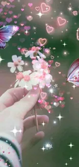 Hand holding flowers with butterflies and glowing hearts on a fantasy wallpaper.