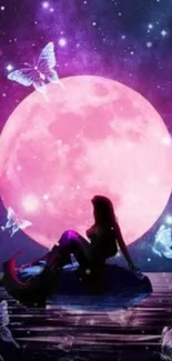 Mermaid silhouetted against a pink moon with butterflies at night.