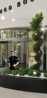 Man at entrance of luxury fashion store with greenery and modern design.