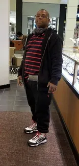 Stylish man in casual attire with headphones in a retail setting.