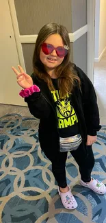 Girl in heart glasses posing with peace sign.