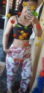 Trendy mirror selfie with floral pants and black top for mobile wallpaper.