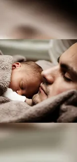 Father holding baby in a cozy brown blanket.