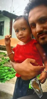 Father holding child in an outdoor setting with green background.