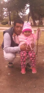 Father and daughter on swing in park.