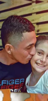 Father kisses daughter, both smiling warmly in cozy setting.