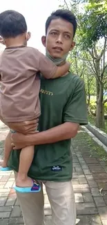 Father holding son in a green park setting.