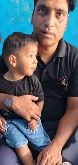 Father and son embracing on blue background.