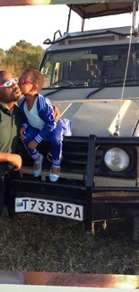 Father and son share a safari moment against a scenic wildlife backdrop.