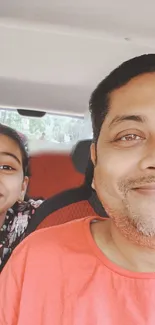 Father and daughter in a car, smiling together.