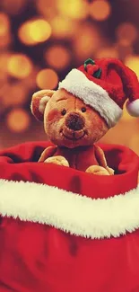 Teddy bear in Santa hat inside red sack with festive bokeh background.