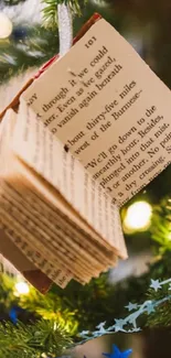 Open book ornament hanging on a colorful, decorated Christmas tree.