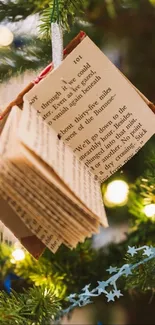 Book ornament hanging on Christmas tree with festive lights.