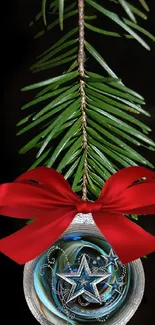 Pine branch with ornament and red bow on black background.