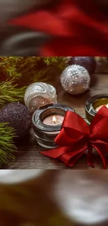 Candles with red ribbon and Christmas ornaments on a wooden table.