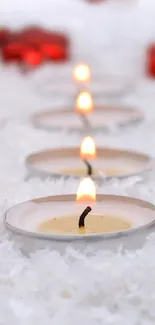 Festive candles and red ornaments on snowy background.