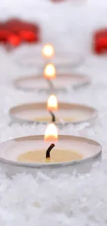 Candlelit scene with red ornaments on snow, perfect for festive ambiance.