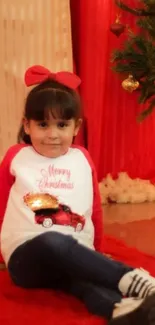 Child sitting by Christmas tree with gifts and festive decor.