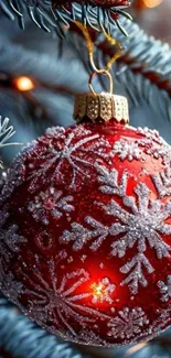Red Christmas bauble with snowflake design on tree.