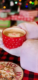 Santa holding a festive red cup with cookies on a plaid table.