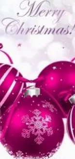 Pink Christmas ornaments on festive wallpaper.