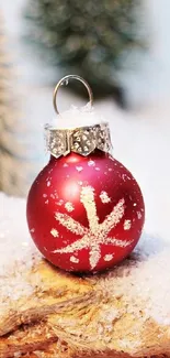 Red Christmas ornament with snow on wood.