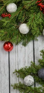 Festive pine branches with red berries and ornaments on a white wood background.