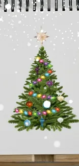 Christmas tree art with colorful ornaments and star topper on a notepad.