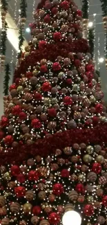 Tall Christmas tree with red ornaments and festive lights.