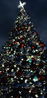 Christmas tree with glowing lights and ornaments under a starry night sky.