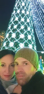 Couple in front of a festive, lit Christmas tree.