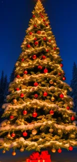 Snowy Christmas tree with glowing lights and red ornaments under a starry sky.