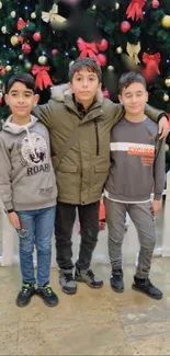 Three kids posing in front of a decorated Christmas tree.