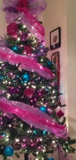 Vibrant Christmas tree with pink ribbons and teal ornaments.