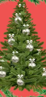 Festive Christmas tree with silver ornaments on a red background.