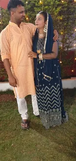 Couple in traditional attire enjoying festive evening outdoors.