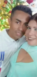 A couple smiling in front of a decorated Christmas tree.