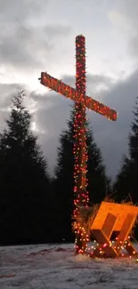 Cross with lights and manger in snow.