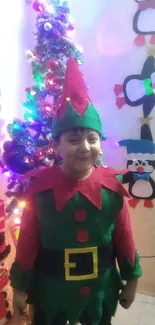 Child in elf costume with Christmas tree and fun decorations.